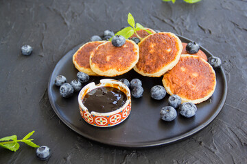 A healthy breakfast of cheese pancakes, berries, and honey. Creative atmospheric decoration