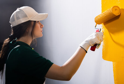 Young women painting a wall with paint roller