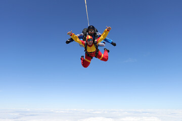 Skydiving. Tandem jump. A happy passenger and her instructor are flying in the sky.