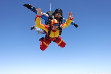 Fototapeta na wymiar Skydiving. Tandem jump. A happy passenger and her instructor are flying in the sky.