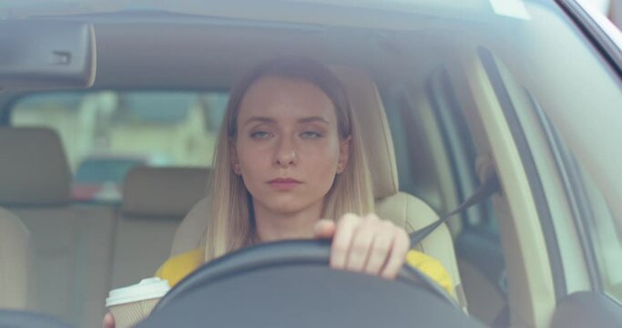 Morning coffee. Happy caucasian woman drinking her hot coffee and looking at the road while driving the car at the sunny morning. Happy start of the day concept