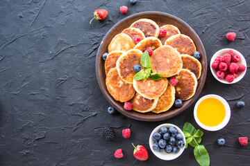 A healthy breakfast of cheese pancakes, berries, and honey. Creative atmospheric decoration
