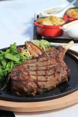 Grilled tomahawk steak on the bone on a ceramic plate horizontal