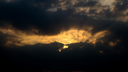 Black around the cloudy sky. The yellow sun is shining in the late afternoon.