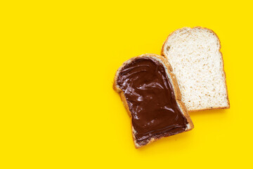 Bread with sweet chocolate hazelnut on yellow background.