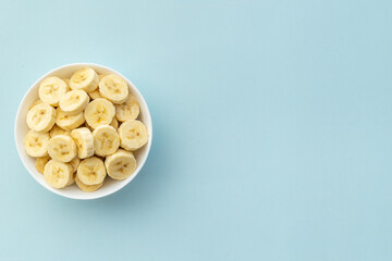 Many banana slices in white bowl. Top view