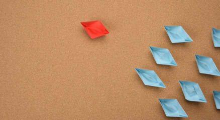 group of paper boats on a brown background. concept of a strong leader in a team, manipulation of...