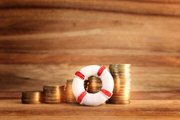 concept image of stacked coins and life bouy over wooden background. banking, funds and assistance...