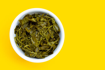 Senna siamea boiled leaves in white bowl on yellow background.