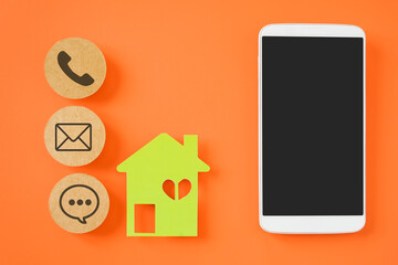 white mobile phone with clipping path on touchscreen, green house paper cut and contact method sign on brown circle paper for work  from home, e-commerce, shopping online, new normal lifestyle concept