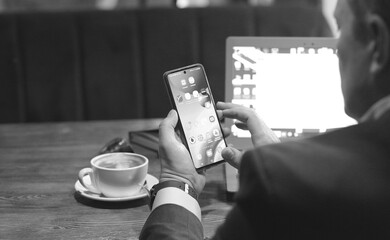 Black and white photo with mens Hand showing online store app on a modern smart phone. Concept of...