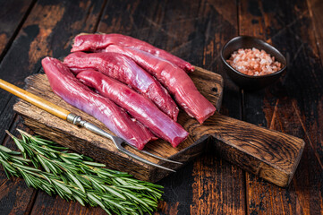 Raw lamb tenderloin Fillet, Mutton Sirloin Meat on wooden board with herbs. Dark wooden background....