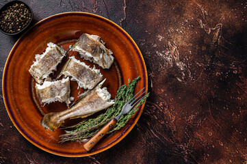 Baked cod white fish in a plate. Dark wooden background. Top view. Copy space