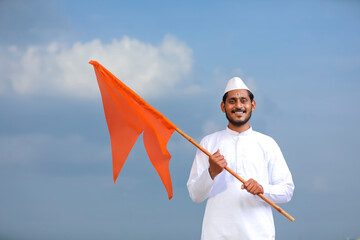 Young indian man (pilgrim) in traditional wear and waving religious flag.