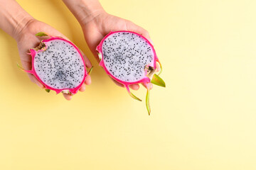 Dragon fruit or pitaya holding by woman hand on yellow background, Tropical fruit