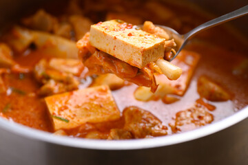 Kimchi soup with tofu and pork cooking in pot and eating by spoon, Korean food - obrazy, fototapety, plakaty