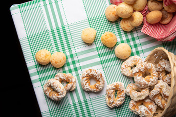 Brazil cheese bread and sweet biscuit on a table with green checkered tablecloth, top view.