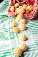 Brazil Cheese Bread, cheese buns falling from a box onto a green checkered tablecloth, selective focus.