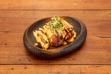 Chicken wings recipe revised with techno-emotional techniques on a beautiful deep plate with sprouts of vegetables