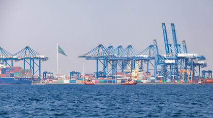 Gantry cranes unload container ships on a sunny summer day