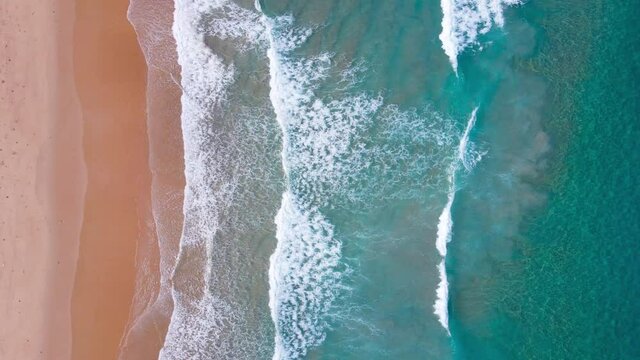 Top-down drone view on the Andaman coast. The sea and large ripples that wash against the shore are filled with beautiful soft white sponges.