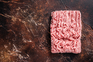 Raw ground chicken or turkey meat on brown table. Dark background. Top View. Copy space