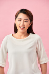 Fototapeta premium Young working woman smiling and looking at camera, standing on pink background.