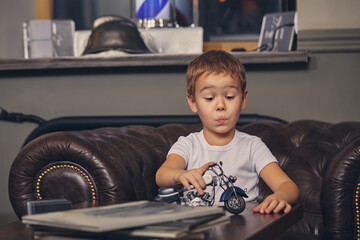 Little boy at the barbershop, in waiting room waiting for master.