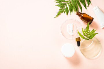 Cosmetic laboratory concept. Glass petri dish with different cosmetic products and green plants. Top view with copy space at pastel background.