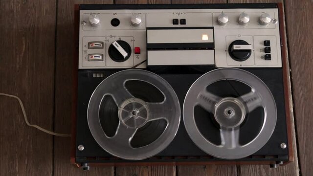 Rotating vintage music player close up. Reel to reel tape recorder playing. Retro tape. View from above. Popular Disco Trends 60s, 70s, 80s, 90s. On a plank floor.