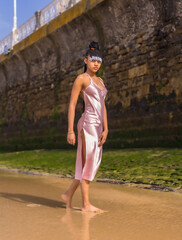 Dominican ethnic girl with braids with a beautiful pink dress. Fashion enjoying the summer walking on the beach