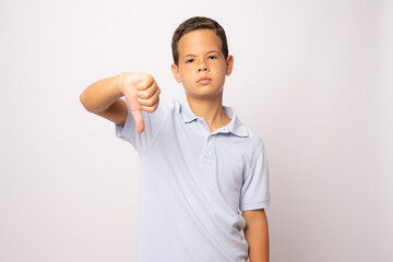 Portrait unhappy, angry, displeased child giving thumbs down hand gesture, isolated on white background.