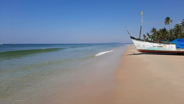 fishing boat on the beach, blue water beach with palm trees, Colva beach in goa, palm tree in beach, tropical beach, blue water and blue sky Arabian sea beach in India, white sand and blue water.