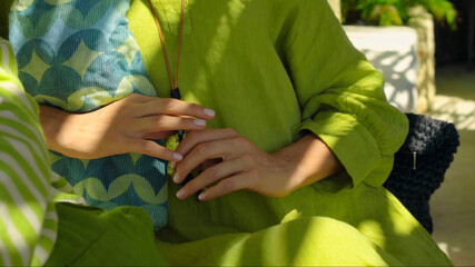 Obraz premium girl touches a green dress with her hand sitting on a bench in the backyard