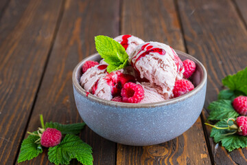 Balls of raspberry ice cream with fresh raspberries in a ceramic bowl on a brown wooden background. Ice cream recipes.