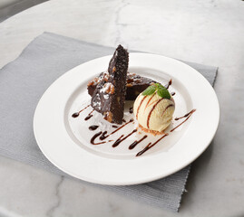 walnut chocolate brownie with vanilla ice cream and peanut, chocolate sauce, mint leaf dessert on round plate western pastry halal menu