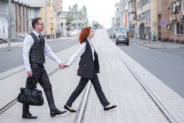 Redhead husband and wife cross the railroad tracks. Walk in the street