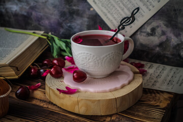 white cup with tea, coffee and red cherries