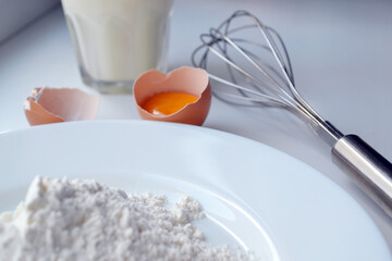 Ingredients and Tools for Baking. Plate of Flour, Broken Egg with Yolk, Whisk and Glass of Milk. Backdrop for menu, restaurant, bakery or bakeshop.