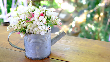 Bouquet, bunch of  flowers in zinc metal watering can on wooden table.