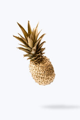 Levitate golden pineapple with shadow against bright background. Minimal summer fruit creative concept.