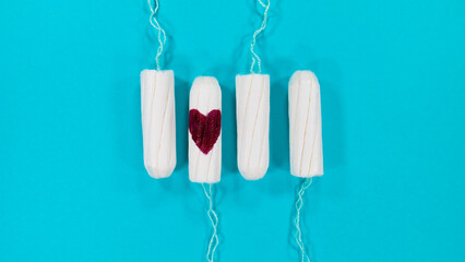 Tampons with heart-shaped drops of blood on a blue background. Negative space or copy space for...