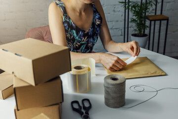 woman preparing parcel shipping label at home for order delivery. small online business