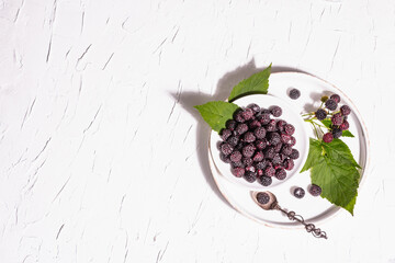 Black raspberry in a white bowl. Ripe organic fruits on the white putty background