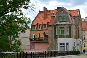 Fototapeta na wymiar A view of an old abandoned historic buildings with some modern extensions standing in the middle of an old city next to a medieval bridge made out of stone and metal spotted on a Polish countryside
