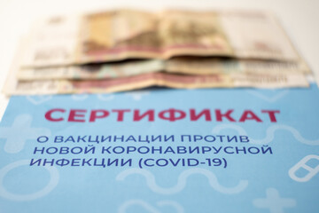 Close-up of the vaccination certificate and money. Selective focus. Sale of certificates by fraudsters. Inscription in Russian: certificate of vaccination against COVID-19