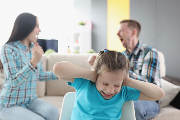 Little girl closing her ears against background of swearing parents at home