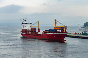 The photo shows a cargo ship docking in the harbor of Bergen