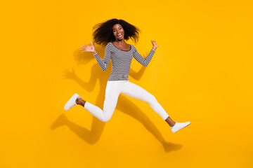 Fototapeta na wymiar Full length body size photo woman in white pants jumping up laughing isolated vibrant yellow color background