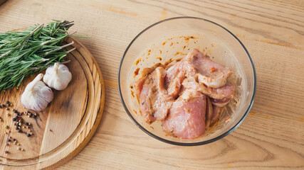 top view of marinated sliced chicken with rosemary in bowl